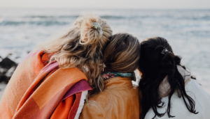 three women on the beach, photographed from the back